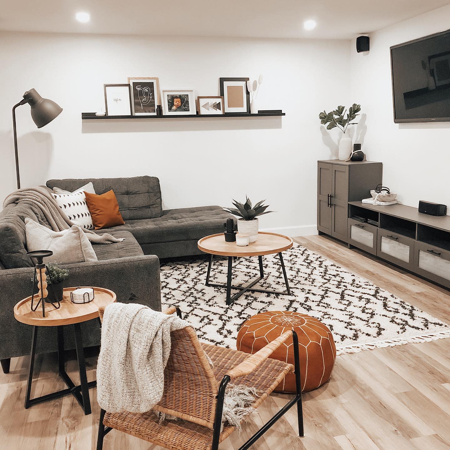 Cozy living room with gray sectional, woven chair, patterned rug, and wooden accents.